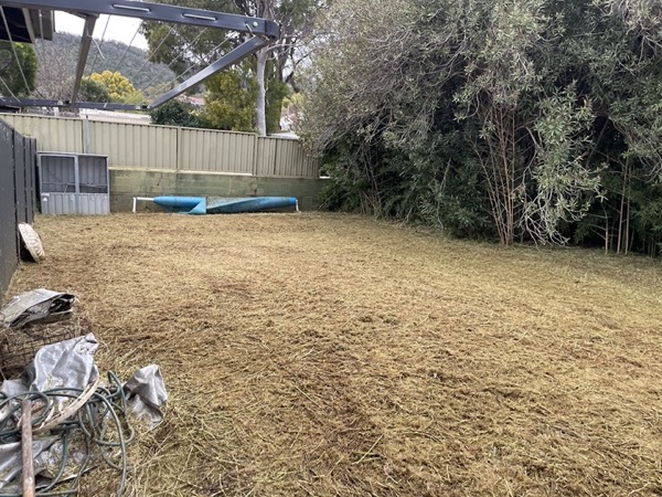 A cleared back yard raked down to bare ground beside a shed