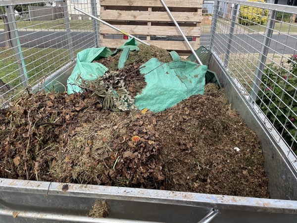 A caged trailer filled to the rails with a load of dark garden mulch