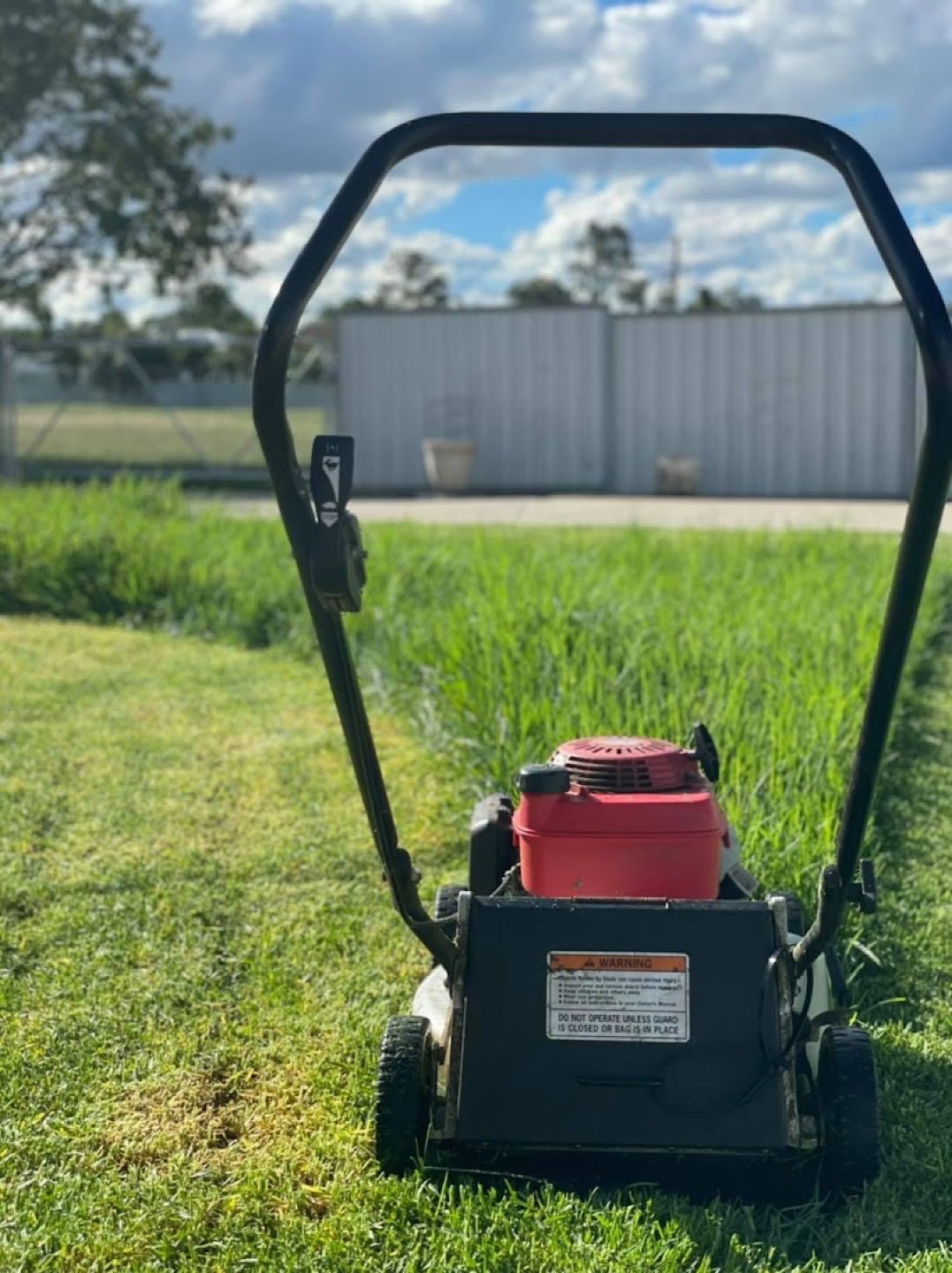 A mower part way through a strip of long green grass