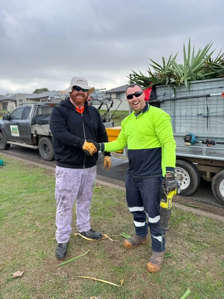 Two workers shaking hands beside a trailer loaded with cut palm fronds